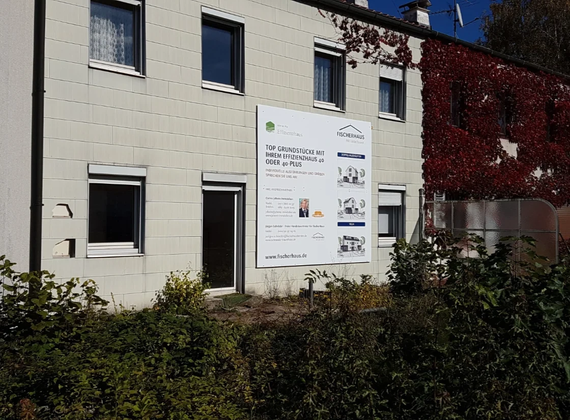 Großes Schild aus Aluminium-Verbundplatte mit bedruckter Folie an der Wand eines Hauses